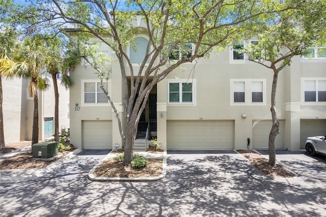 multi unit property with an attached garage, driveway, and stucco siding