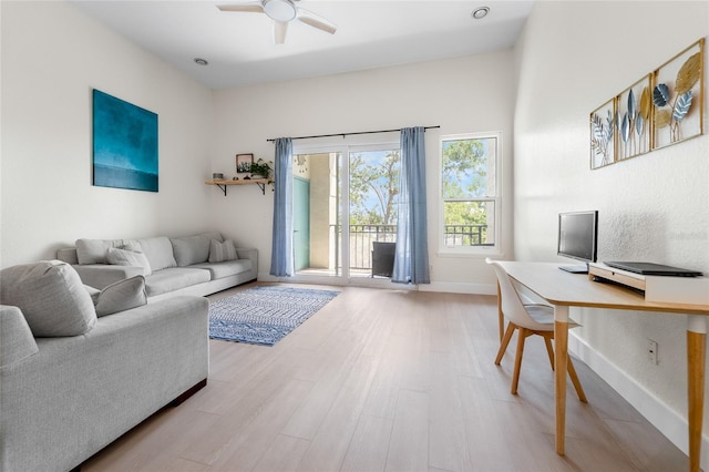 living room with light wood-style floors, a ceiling fan, and baseboards