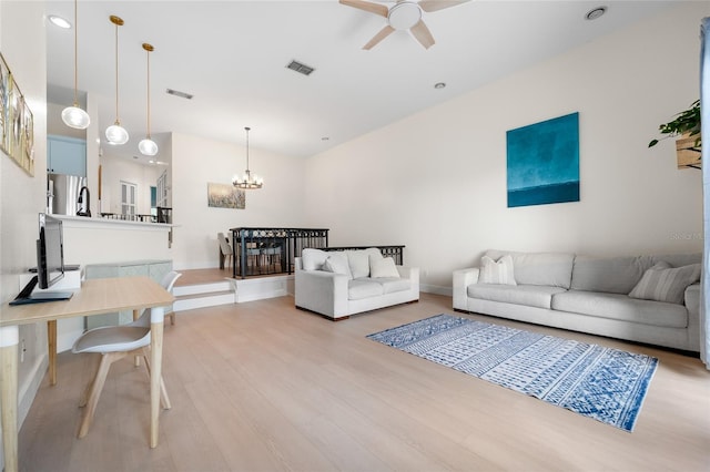 living room with baseboards, visible vents, wood finished floors, and ceiling fan with notable chandelier