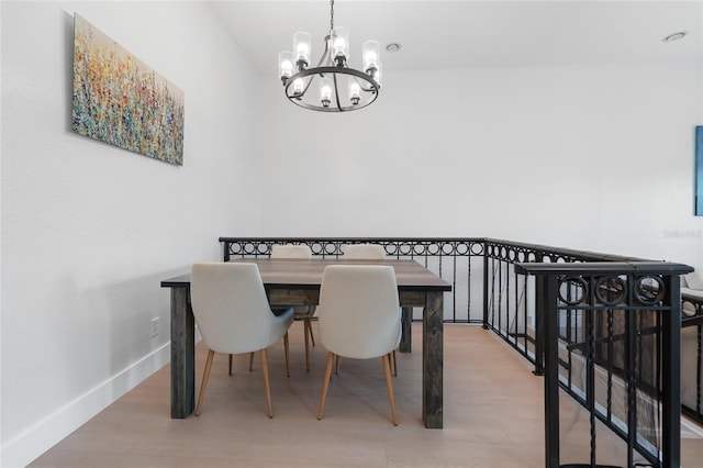 dining area featuring baseboards, light wood-type flooring, and a chandelier