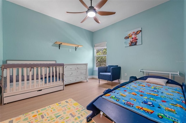 bedroom featuring baseboards, ceiling fan, wood finished floors, and baseboard heating