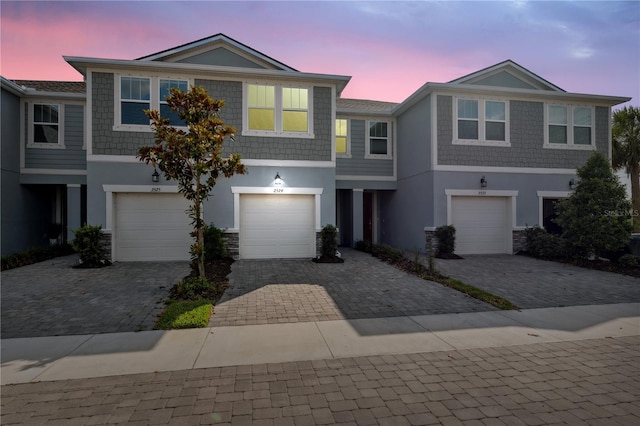 view of property with an attached garage, stucco siding, and driveway
