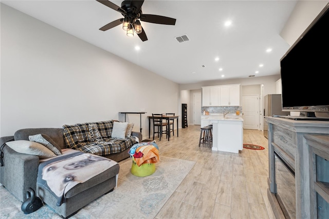 living room with light wood-type flooring, visible vents, ceiling fan, and recessed lighting