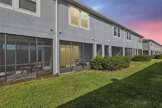 back of property featuring a lawn and stucco siding