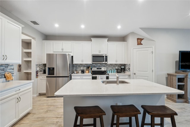 kitchen featuring a sink, stainless steel appliances, backsplash, and a breakfast bar area