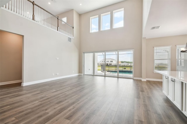 34084 Torrent Ln, Wesley Chapel, FL 33543 - unfurnished living room featuring a towering ceiling, dark wood-type flooring, and baseboards