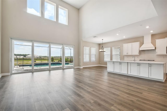 34084 Torrent Ln, Wesley Chapel, FL 33543 - unfurnished living room with a high ceiling, wood finished floors, a chandelier, baseboards, and recessed lighting