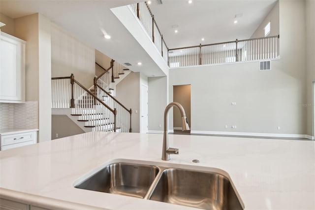 34084 Torrent Ln, Wesley Chapel, FL 33543 - kitchen with a sink, a high ceiling, white cabinetry, backsplash, and recessed lighting