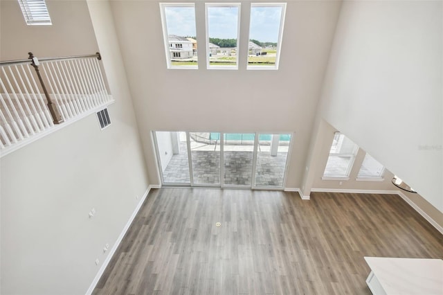 34084 Torrent Ln, Wesley Chapel, FL 33543 - unfurnished living room with baseboards, wood finished floors, and a towering ceiling