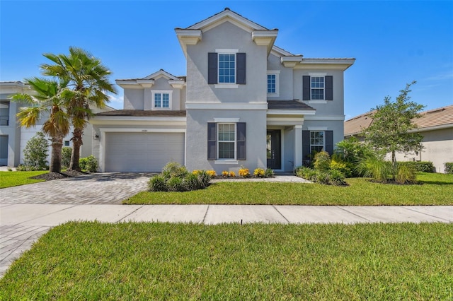 34084 Torrent Ln, Wesley Chapel, FL 33543 - view of front of home featuring stucco siding, decorative driveway, a garage, and a front yard