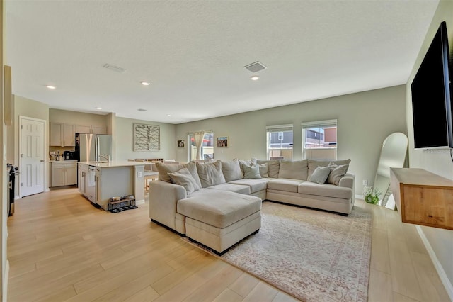 living room with recessed lighting, baseboards, visible vents, and light wood-style floors