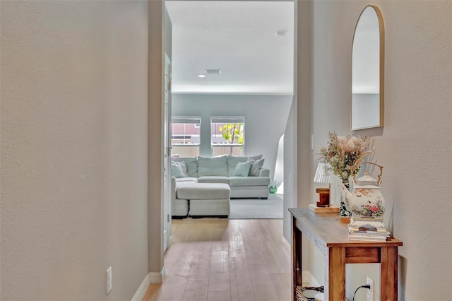 corridor with baseboards and light wood-style flooring