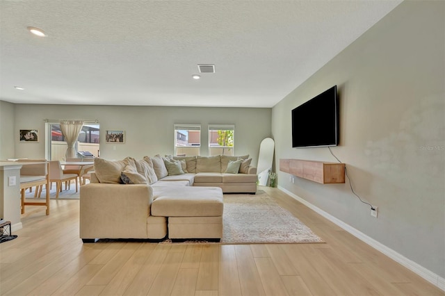 living room featuring recessed lighting, baseboards, visible vents, and light wood-type flooring