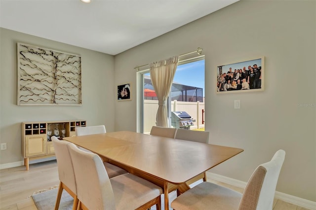 dining space featuring baseboards and light wood-style flooring