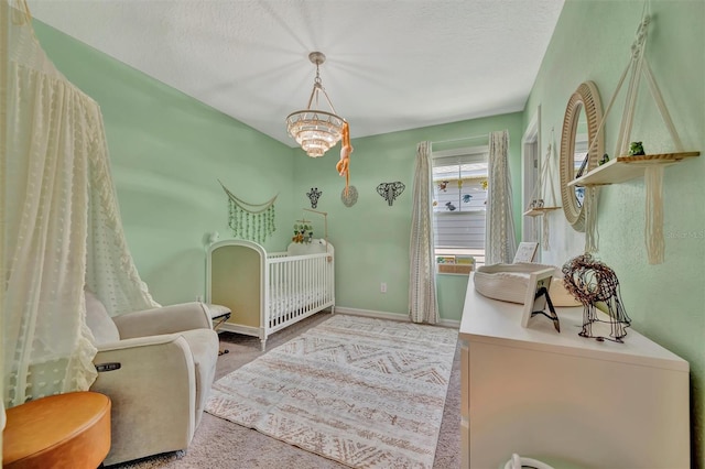 bedroom with carpet floors, a textured ceiling, baseboards, and a nursery area