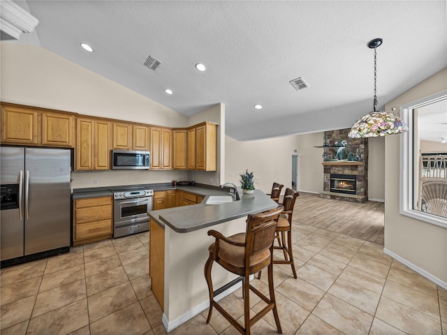 kitchen with a sink, a peninsula, stainless steel appliances, visible vents, and dark countertops