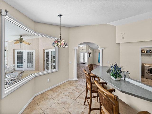 dining room with light tile patterned floors, ornate columns, ceiling fan, arched walkways, and washer / clothes dryer