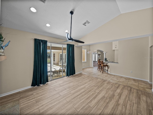 unfurnished living room featuring arched walkways, visible vents, a ceiling fan, and wood finished floors