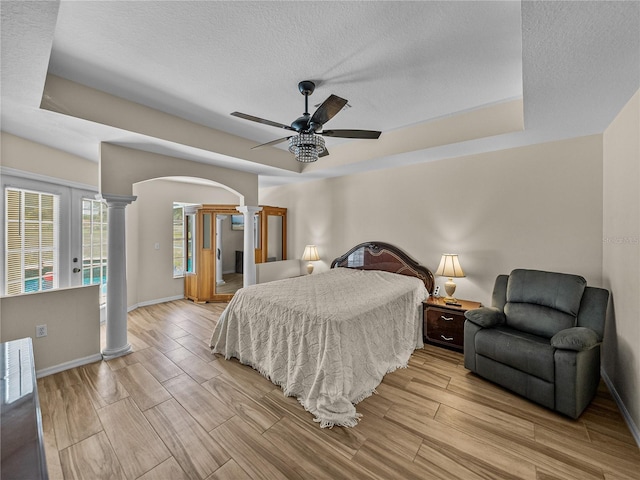 bedroom with baseboards, decorative columns, access to outside, arched walkways, and light wood-style floors