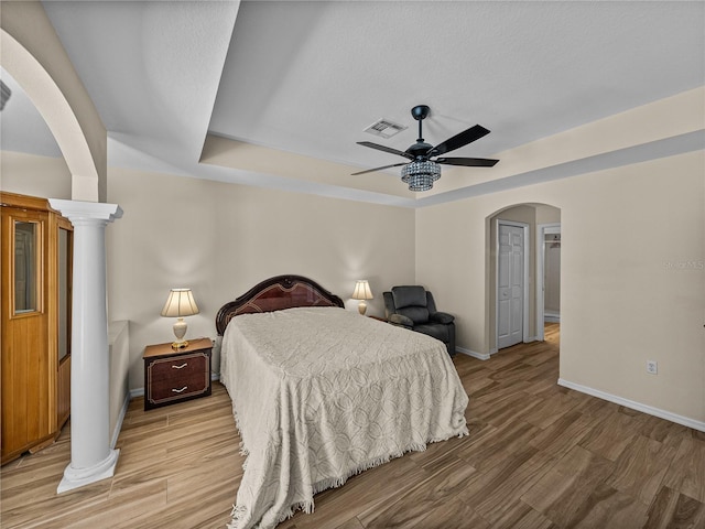 bedroom with visible vents, arched walkways, a ceiling fan, baseboards, and light wood-style floors
