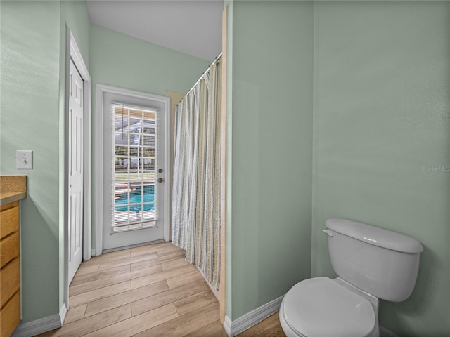 full bathroom with toilet, baseboards, a shower with shower curtain, vanity, and wood finished floors