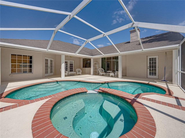 view of swimming pool with a patio, a pool with connected hot tub, french doors, and a lanai