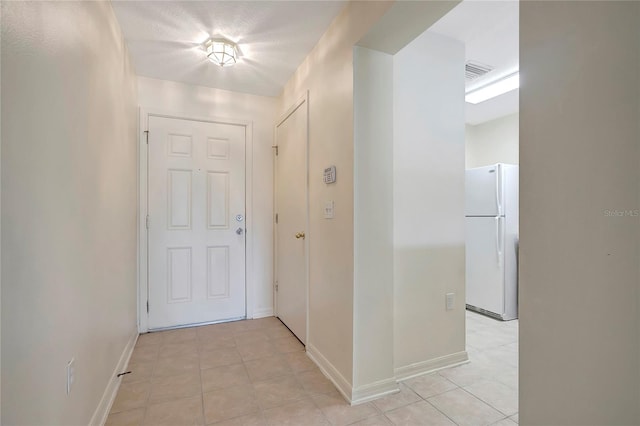 hallway with light tile patterned flooring and baseboards