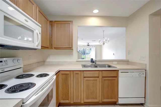 kitchen featuring white appliances, a sink, a chandelier, light countertops, and hanging light fixtures