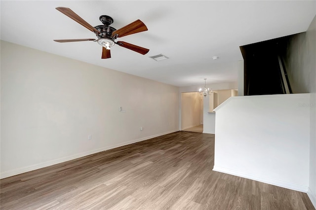 unfurnished living room with light wood-style flooring, a chandelier, a ceiling fan, and baseboards