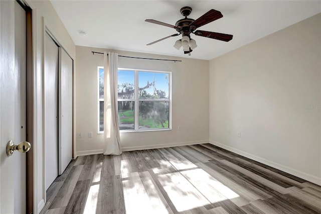 unfurnished bedroom with wood finished floors, baseboards, and a closet