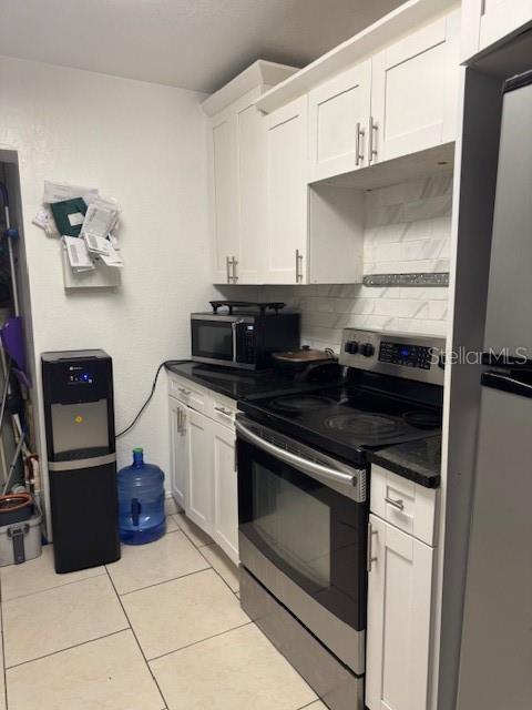 3713 E Clifton St, Tampa, FL 33610 - kitchen featuring stainless steel appliances, dark countertops, light tile patterned floors, and white cabinets