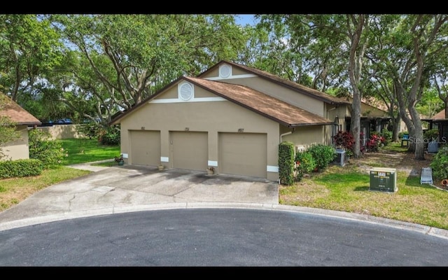 view of front facade with stucco siding, concrete driveway, a front yard, and an attached garage