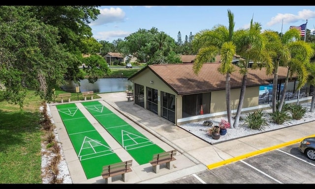 view of home's community featuring shuffleboard, uncovered parking, a lawn, and a water view