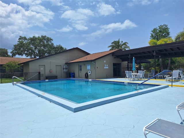 community pool with a patio and fence