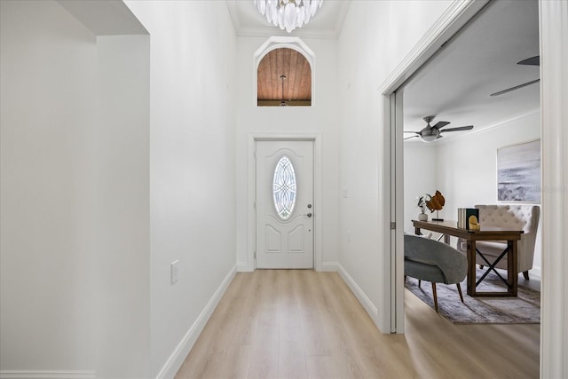foyer entrance featuring crown molding, baseboards, ceiling fan, and light wood-type flooring