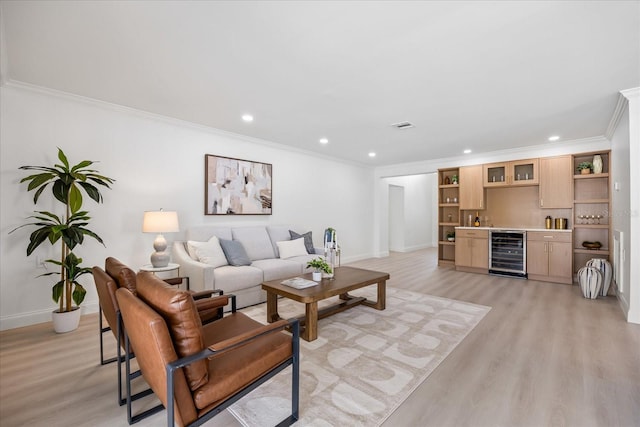 living room featuring crown molding, wine cooler, baseboards, wet bar, and light wood finished floors