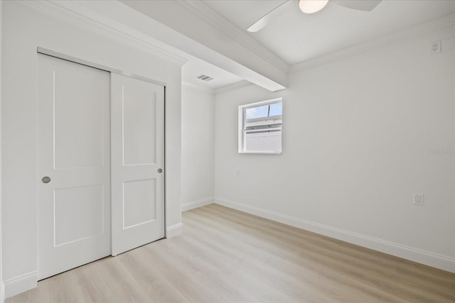 unfurnished bedroom featuring a closet, ornamental molding, visible vents, light wood finished floors, and baseboards
