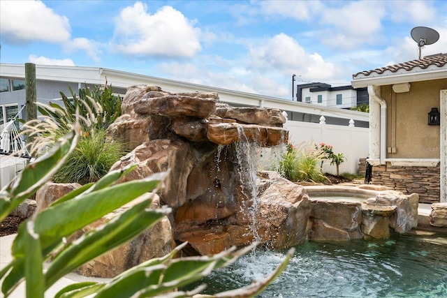 exterior details with a downspout, fence, a jacuzzi, and stucco siding