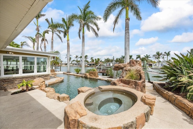 view of pool featuring a water view and an in ground hot tub