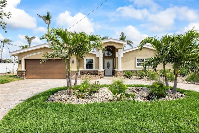7991 1st Ave S, Saint Petersburg, FL 33707 - mediterranean / spanish home with stucco siding, stone siding, decorative driveway, and an attached garage