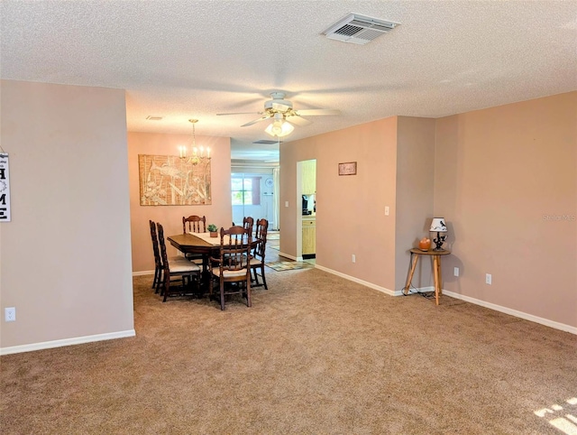 carpeted dining room featuring a textured ceiling, visible vents, baseboards, and ceiling fan with notable chandelier
