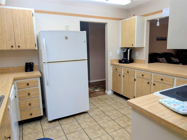 kitchen featuring light countertops, light brown cabinetry, freestanding refrigerator, and light tile patterned flooring