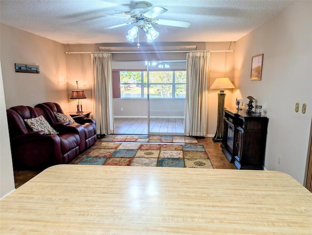 living area featuring a ceiling fan, a textured ceiling, and wood finished floors