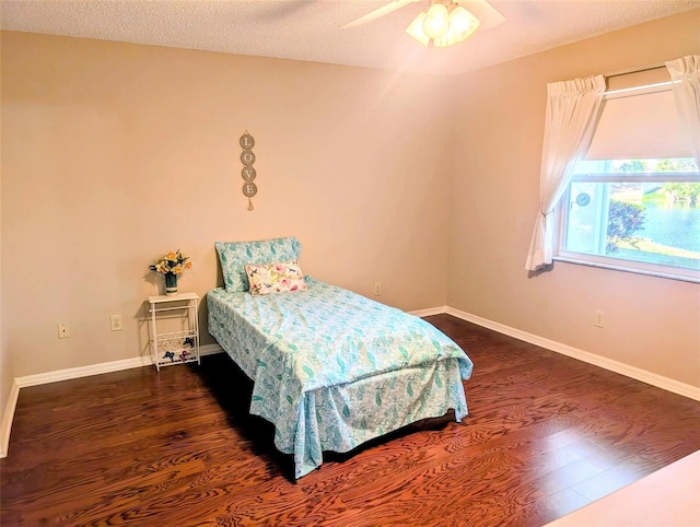 bedroom featuring a textured ceiling, baseboards, a ceiling fan, and wood finished floors