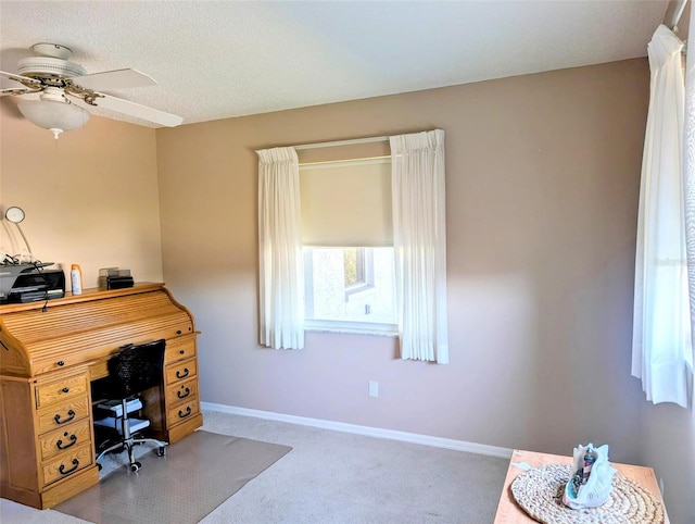 carpeted office space with baseboards and a ceiling fan