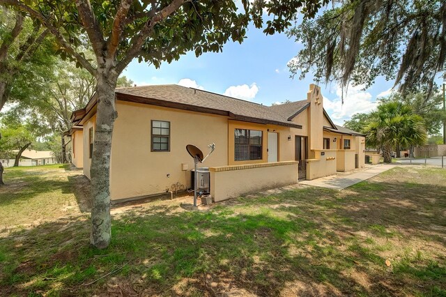 56 Pine Trak Unit 101E, Ocala, FL 34472 - rear view of house with a lawn, stucco siding, and a chimney