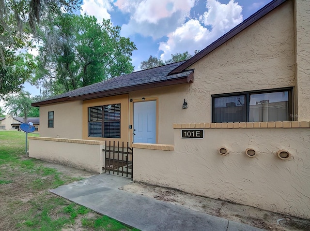 56 Pine Trak Unit 101E, Ocala, FL 34472 - doorway to property featuring fence, a shingled roof, and stucco siding
