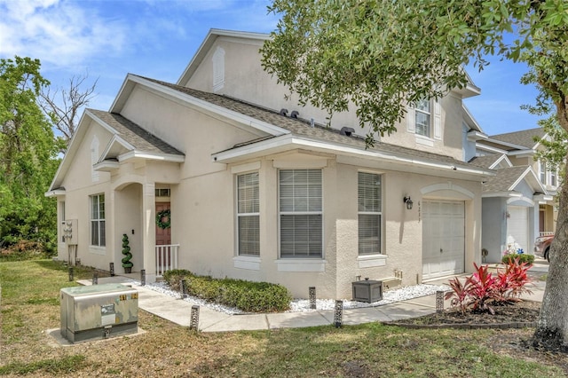 view of front of house with stucco siding, roof with shingles, and a front yard