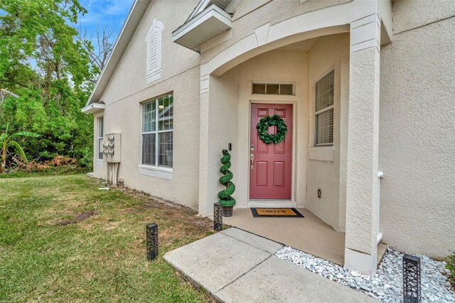 doorway to property featuring stucco siding and a lawn