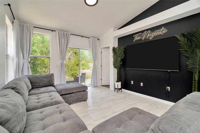 living area featuring lofted ceiling, marble finish floors, and baseboards